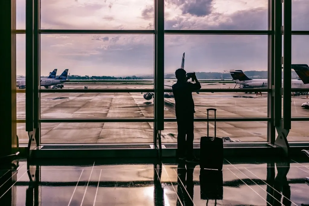 Viajero junto al ventanal de una terminal con aviones en pista